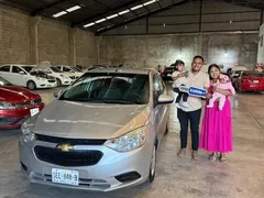 Familia joven con su bebé recibiendo un Chevrolet Aveo plateado de EzRide