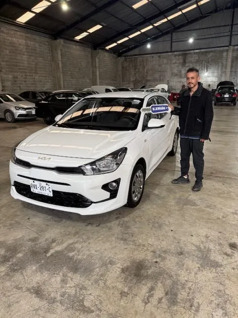 Conductor de plataforma junto a su Kia Rio blanco entregado por EzRide
