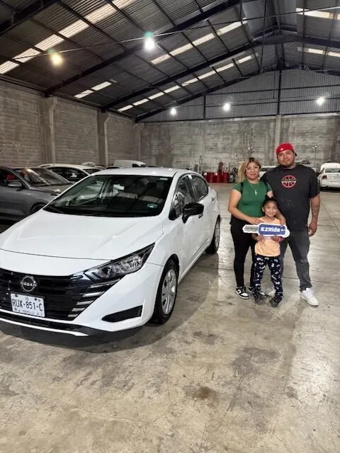 Familia recibiendo las llaves de su Nissan Versa blanco en la entrega de EzRide